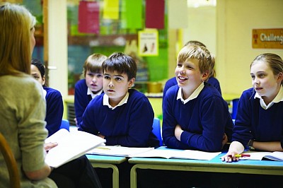 School children seated at there desks paying extra attention to what there teacher is saying
