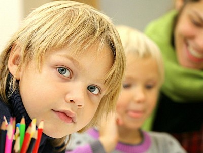 A young girl sitting at a desk focus on the camera. She looking into the lens with curiosity in her eyes