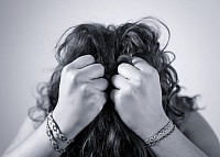 A teacher with dark hair pulling on her hair because of job burnout
