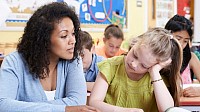 A teacher listening to a student who's going through a rough time. There sitting at a table in a classroom